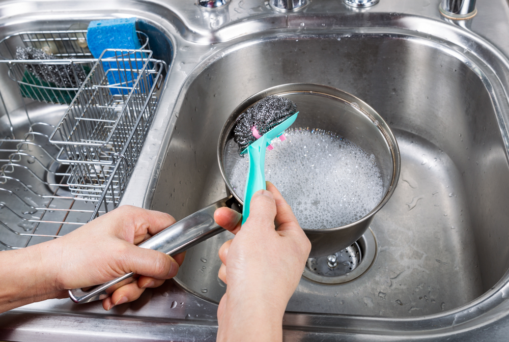 Cleaning dishes with a metal sponge.